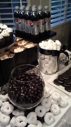 a table topped with lots of different types of donuts next to bottles of soda