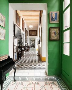 the hallway is painted bright green and has many pictures on the wall, including an old piano