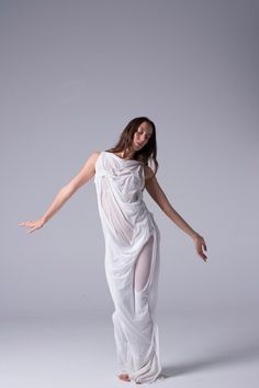 a woman in a white dress posing for the camera with her arms spread wide out