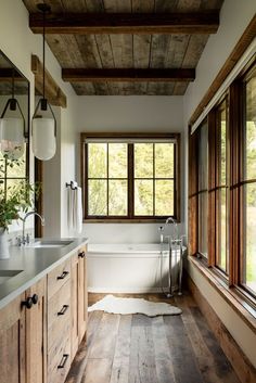 a bathroom with wooden floors and white walls, along with a large tub in the center