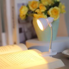 an open book sitting on top of a table next to a desk with a lamp