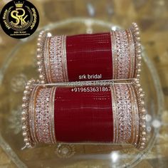 two red and gold bangles are sitting on a glass plate