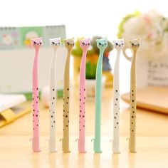 four different colored toothbrushes with cats on them sitting in front of a desk