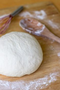 a ball of dough sitting on top of a wooden cutting board