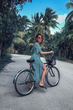 a woman in a blue dress is sitting on a bicycle