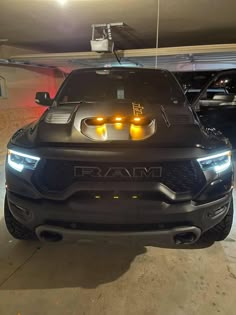 the front end of a black truck with two yellow lights on it's hood