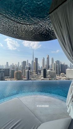 an outdoor pool with cityscape in the background and curtains on the ceiling above it