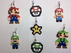 four pixel keychains are shown in different colors and sizes, each featuring an image of mario