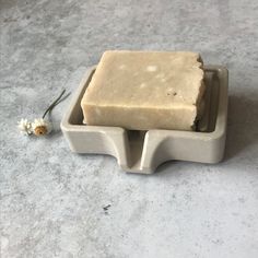 a soap bar sitting on top of a counter next to a small white daisy flower