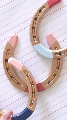 a pair of pink, blue and gold horseshoes on top of lined paper