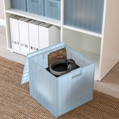 a blue storage box with headphones in it on the floor next to bookshelves