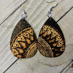 a pair of brown and black earrings sitting on top of a wooden table