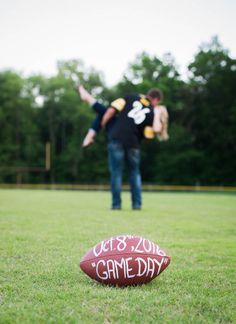 a football sitting on top of a lush green field next to a man holding a frisbee