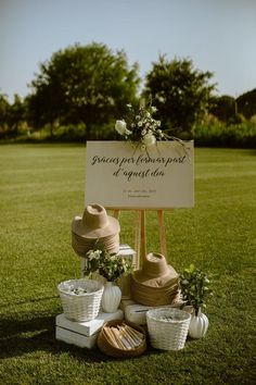 a sign that is sitting in the grass with some hats on it's stand