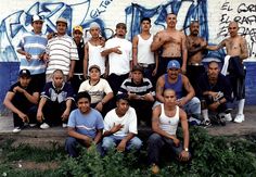 a group of men standing next to each other in front of a wall with graffiti on it