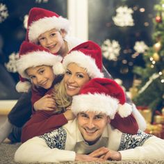 a group of people wearing santa hats in front of a christmas tree