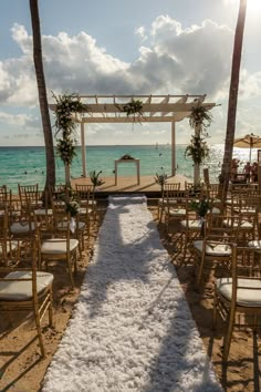 an outdoor wedding setup on the beach with white carpet and palm trees in the foreground