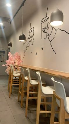 a long table with white chairs in front of a wall that has coffee cups on it