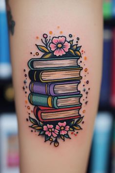 a tattoo with books and flowers on it