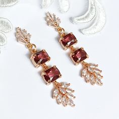 Bridal Art Deco style earrings, beautiful boho chic style with gold plated clear baguette cut fan studs, suspended is a double rectangle drop of rich emerald cut burgundy crystals,  finished with marquise cut clear autumn leaves, gold plated finish. Louisa Grace Jewellery. For the bride of today and the heirlooms of tomorrow. All earrings are designed with high end European crystals and are handset.  Measurements: length from top of hook approx 5.4 cms, width at widest point 1.1 cms Our jeweller Clear Autumn, Burgundy Earrings, Bridal Art, Boho Chic Fashion, Emerald Cut, Art Deco Fashion, Autumn Leaves, The Bride, Jewelry Earrings Dangle