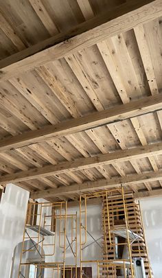 an unfinished room with wooden ceiling and ladders