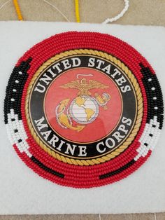 the united states marine corp logo is made out of bead and thread on a piece of paper