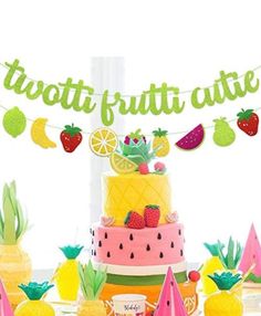 a table topped with a cake and lots of fruit on top of it next to pineapples