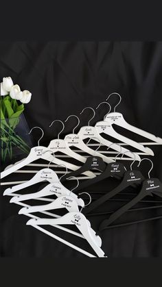 a bunch of clothes hangers sitting next to a vase with flowers in it on a black background