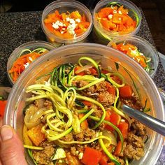 a person holding a fork in a bowl filled with vegetables, meat and veggies