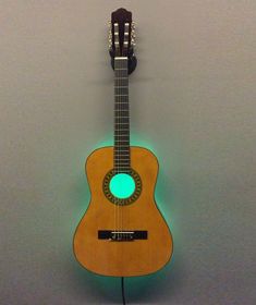 an acoustic guitar is mounted to the wall with a green light on it's side