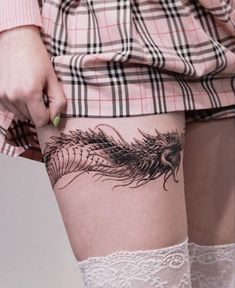 a woman's thigh with a feather tattoo on it