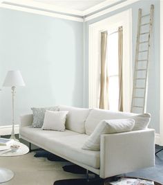 a living room with white furniture and blue walls