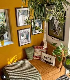 a living room filled with lots of plants and pictures on the wall next to a couch