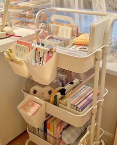 a white cart filled with lots of books next to a window