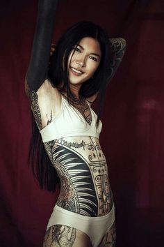 a woman with tattoos on her body posing for the camera and holding up her arm