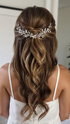 a woman with long hair wearing a white dress and a headpiece that has leaves on it