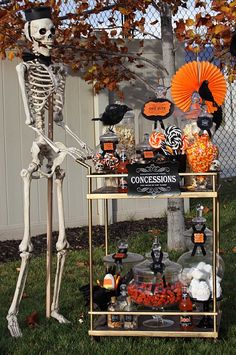 a halloween party with skeletons and pumpkins on the table, in front of a sign that says concesions