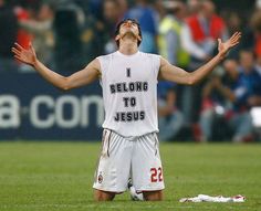 a man standing on top of a soccer field holding his hands up in the air