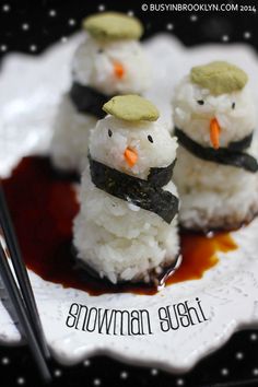 three snowmen are sitting on a plate with chopsticks