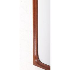 a wooden mirror hanging on the wall next to a white wall with a brown frame