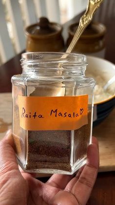 a person holding a jar with spices in it and a spoon sticking out of it