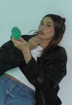 a woman sitting on the ground holding a green frisbee in her right hand