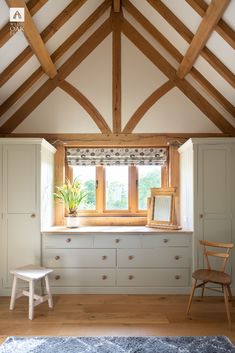 a room with white furniture and wooden beams on the ceiling, along with a window