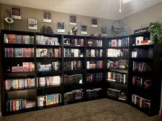 a room with several bookshelves and pictures on the wall above them, along with carpeted flooring