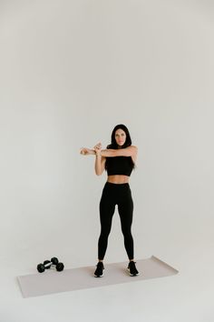 a woman in black top and leggings holding a barbell