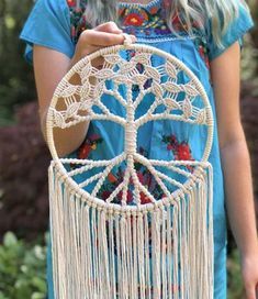 a woman is holding a white dream catcher in her hands and wearing a blue shirt