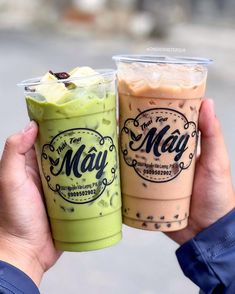 two people are holding up cups with drinks in them, one is green and the other is brown