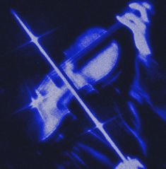 a violin that is in the dark with blue lights on it's side and an image of someone holding their hand up