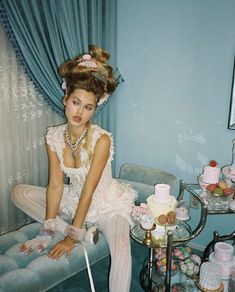 a woman is sitting on a couch in a room with cakes and cupcakes