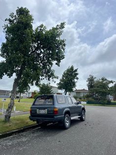 a car parked on the side of a road next to a tree